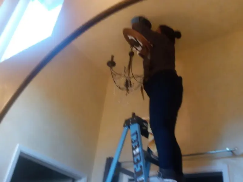 Electrician installing a chandelier in a Hibbing residence